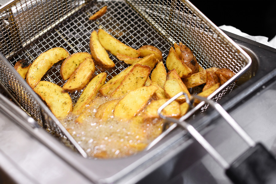 spicy potato chips or wedges in a deep fryer