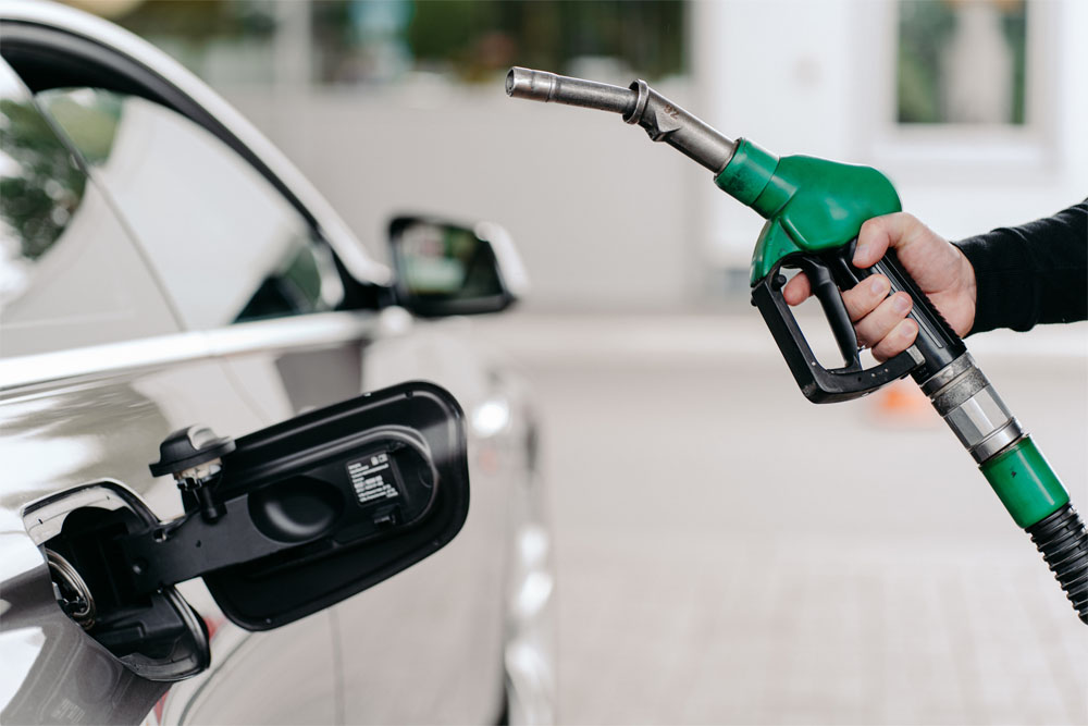 cropped shot of mans hand pumping gasoline fuel in car at gas station. auto being filled with petrol. unrecognizable man holds fuel nozzel.